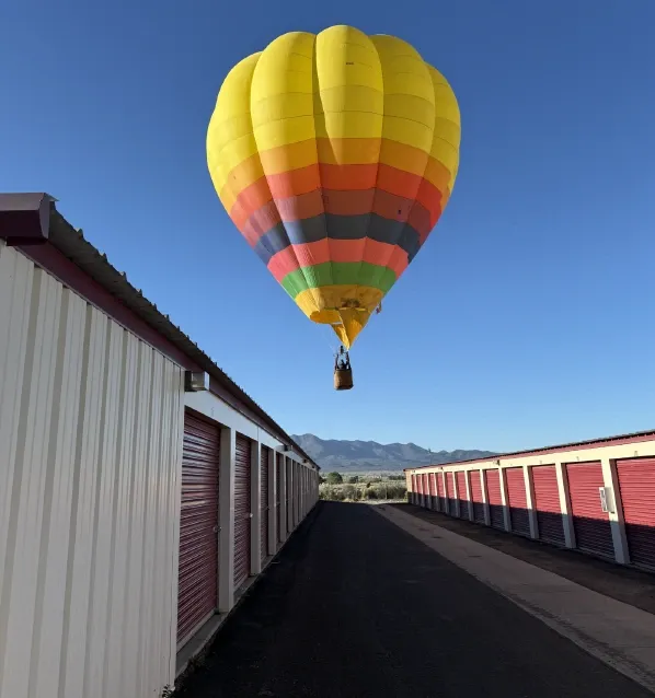 Colorful hot air balloon above Alices Attic Self Storage units on beautiful sunny day