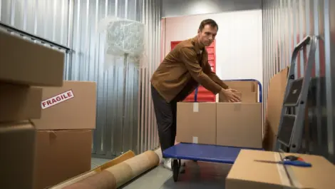 White man stacking boxes inside a storage unit